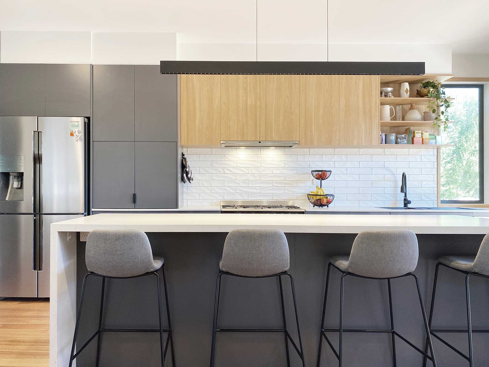 Modern kitchen with a wooden island, gray stools, stainless steel fridge, and open shelving with decor. Modern kitchen with a wooden island, gray stools, stainless steel fridge, and open shelving with decor.