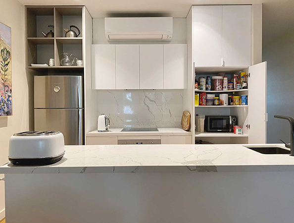 Modern kitchen with white cabinets, open pantry, fridge, toaster, and marble countertop. Modern kitchen with white cabinets, open pantry, fridge, toaster, and marble countertop.