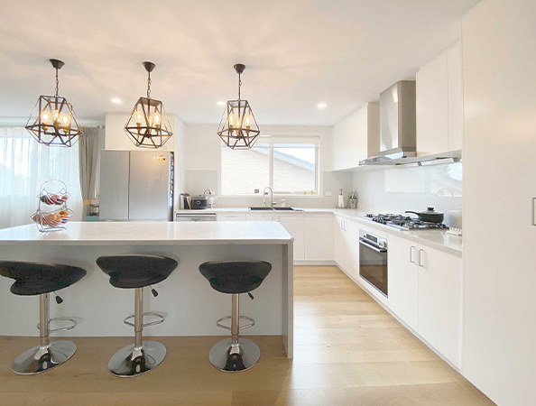 Modern kitchen with white cabinets, island with stools, pendant lights, and stainless steel appliances. Modern kitchen with white cabinets, island with stools, pendant lights, and stainless steel appliances.