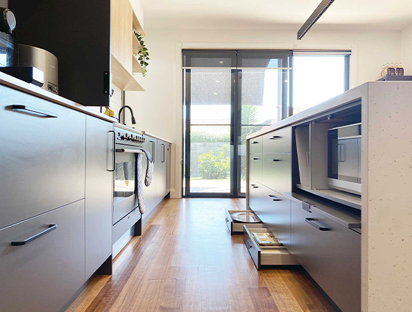 Modern kitchen with sleek cabinets, an oven, and a microwave. Light streams in from large sliding glass doors. Modern kitchen with sleek cabinets, an oven, and a microwave. Light streams in from large sliding glass doors.
