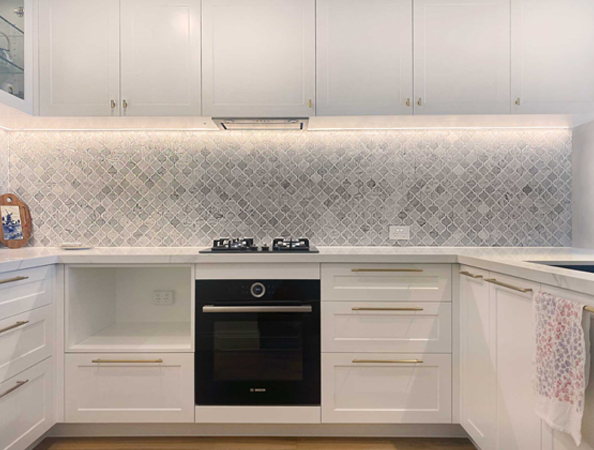 Modern kitchen with white cabinets, patterned backsplash, and a black oven with a gas cooktop. Modern kitchen with white cabinets, patterned backsplash, and a black oven with a gas cooktop.