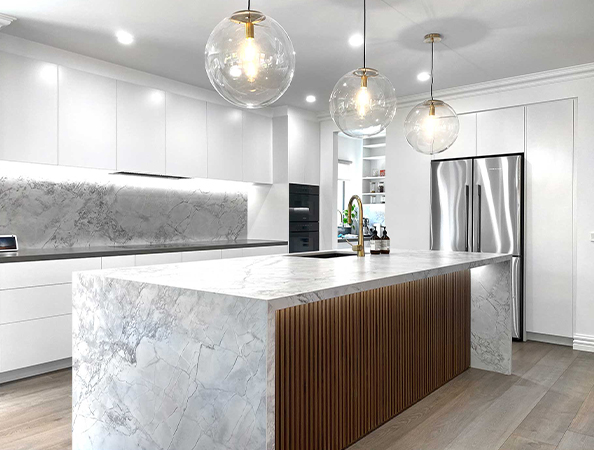Modern kitchen with marble island, globe pendant lights, white cabinets, and stainless steel appliances. Modern kitchen with marble island, globe pendant lights, white cabinets, and stainless steel appliances.