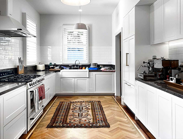 A bright kitchen with white cabinets, a farmhouse sink, and a patterned rug on wooden flooring. A bright kitchen with white cabinets, a farmhouse sink, and a patterned rug on wooden flooring.