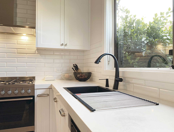 Modern kitchen with white cabinets, black faucet, and large window overlooking greenery. Modern kitchen with white cabinets, black faucet, and large window overlooking greenery.