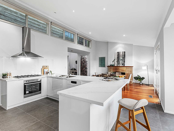 Modern kitchen with white countertops, stainless steel appliances, and an island. Adjacent dining area with wooden floor. Modern kitchen with white countertops, stainless steel appliances, and an island. Adjacent dining area with wooden floor.