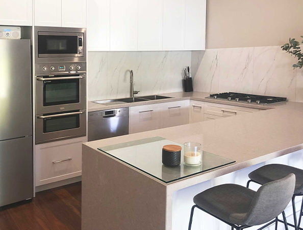 Modern kitchen with stainless steel appliances, marble backsplash, and a breakfast bar with two stools. Modern kitchen with stainless steel appliances, marble backsplash, and a breakfast bar with two stools.