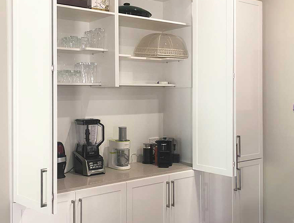 White kitchen cabinets with doors open, revealing glasses, a blender, a coffee maker, and kitchenware inside. White kitchen cabinets with doors open, revealing glasses, a blender, a coffee maker, and kitchenware inside.