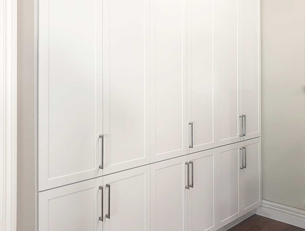 White built-in cabinets with silver handles against a wall. White built-in cabinets with silver handles against a wall.