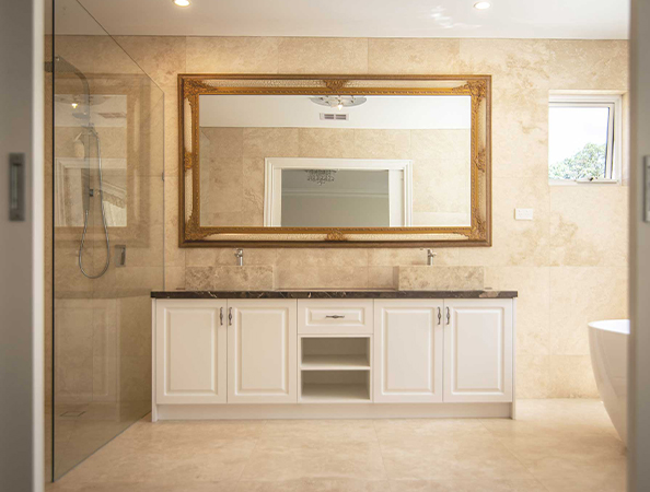 Elegant bathroom with large mirror, dual sinks on a marble-topped white vanity, and glass shower enclosure.