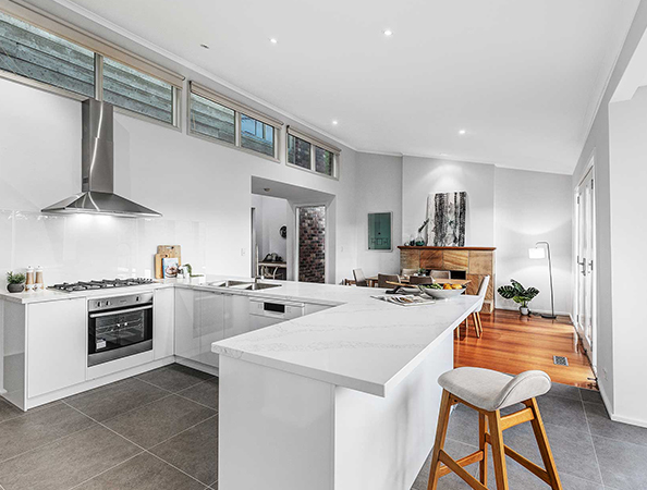 Modern kitchen with white cabinets, marble countertops, bar stool, and dining area in a bright open-concept space. Modern kitchen with white cabinets, marble countertops, bar stool, and dining area in a bright open-concept space.