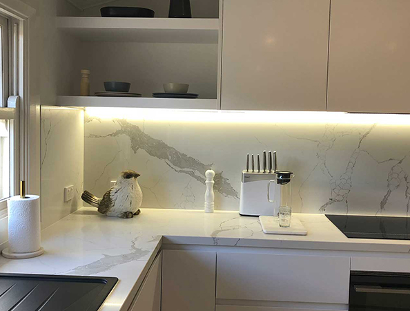 Modern kitchen with marble countertops, a coffee maker, knife set, and bird sculpture under warm recessed lighting. Modern kitchen with marble countertops, a coffee maker, knife set, and bird sculpture under warm recessed lighting.