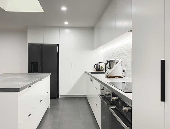 Modern kitchen with white cabinets, black appliances, and a sleek countertop.