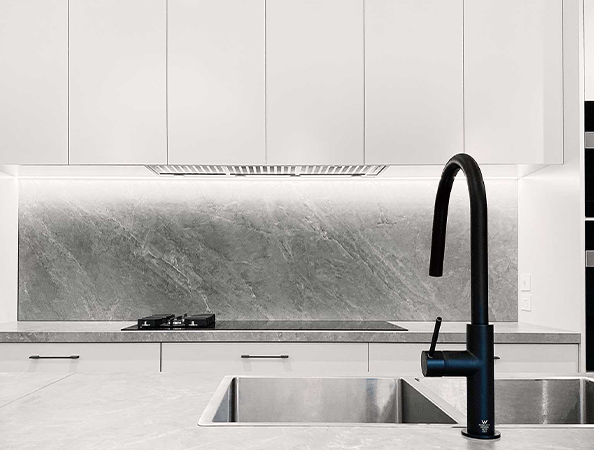 Modern kitchen with a black faucet, dual sink, gas stove, and a gray marble backsplash under white cabinets. Modern kitchen with a black faucet, dual sink, gas stove, and a gray marble backsplash under white cabinets.