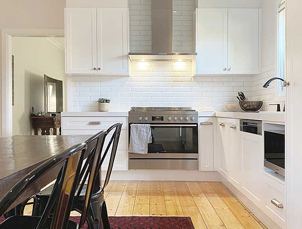 Modern kitchen with white cabinets, stainless steel appliances, and a wooden dining table with black chairs. Modern kitchen with white cabinets, stainless steel appliances, and a wooden dining table with black chairs.