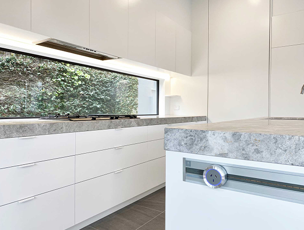 Modern kitchen with white cabinets, grey countertop, and a large window showcasing greenery. Modern kitchen with white cabinets, grey countertop, and a large window showcasing greenery.