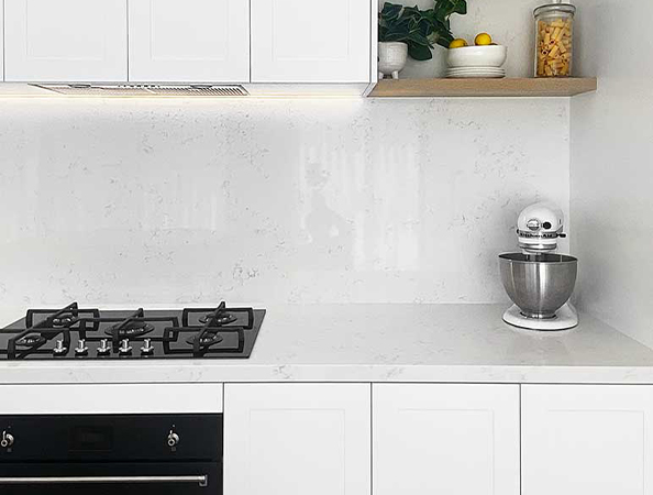 Modern kitchen with white cabinets, gas stove, mixer, and shelf holding plants and a jar.