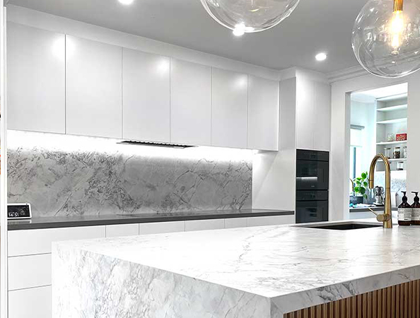 Modern kitchen with white cabinets, marble countertops, and pendant lights. Modern kitchen with white cabinets, marble countertops, and pendant lights.