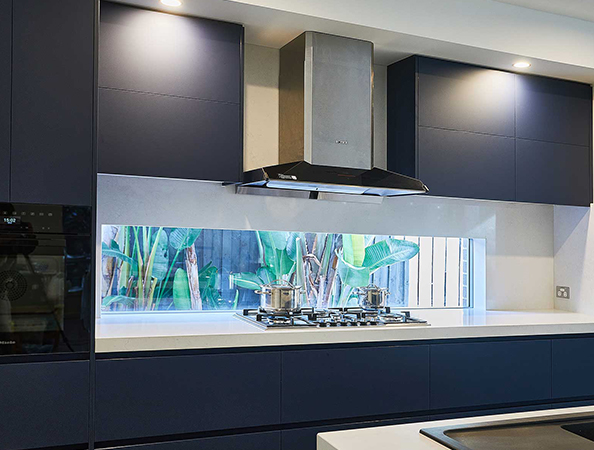 Modern kitchen with dark cabinets, stainless steel stove and hood, and a window view of green plants outside. Modern kitchen with dark cabinets, stainless steel stove and hood, and a window view of green plants outside.