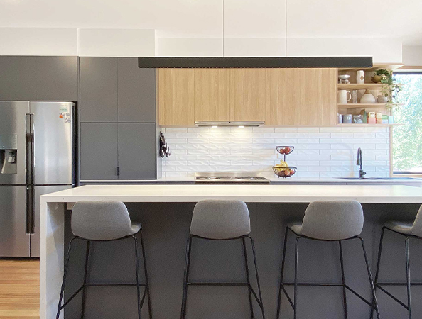 Modern kitchen with gray cabinets, a white counter, bar stools, and natural light from a large window. Modern kitchen with gray cabinets, a white counter, bar stools, and natural light from a large window.