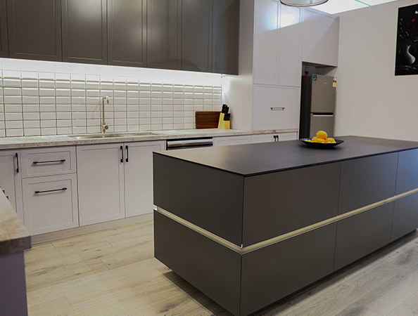 Modern kitchen with gray island, white cabinetry, stainless steel appliances, and a fruit bowl on the counter. Modern kitchen with gray island, white cabinetry, stainless steel appliances, and a fruit bowl on the counter.
