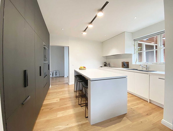 Modern kitchen with black and white cabinets, island with stools, wooden floor, and recessed lighting. Modern kitchen with black and white cabinets, island with stools, wooden floor, and recessed lighting.