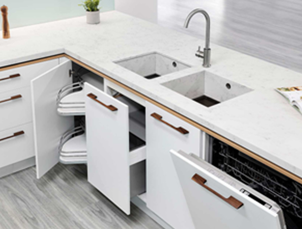 Modern kitchen with white cabinets, open drawers, a double sink, and a visible dishwasher. Plant on countertop.