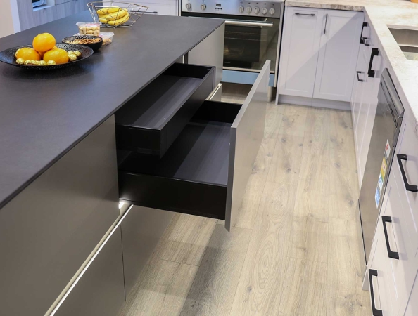 Modern kitchen with an open drawer on a black island, fruit bowl, and sleek appliances under soft lighting. Modern kitchen with an open drawer on a black island, fruit bowl, and sleek appliances under soft lighting.