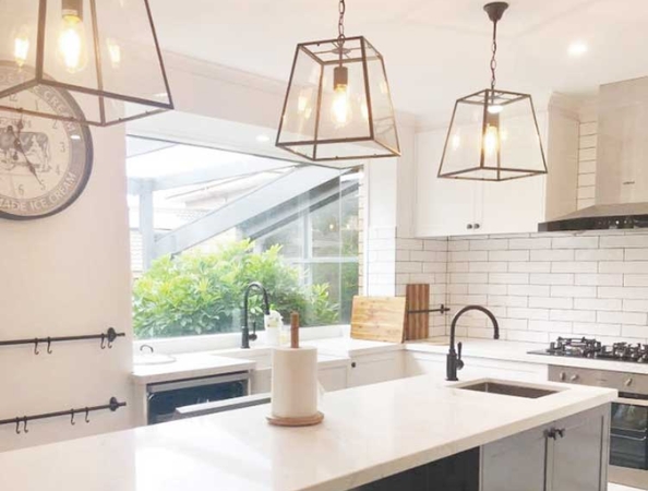 Modern kitchen with white cabinets, subway tiles, large island, pendant lights, and a window with greenery outside. Modern kitchen with white cabinets, subway tiles, large island, pendant lights, and a window with greenery outside.