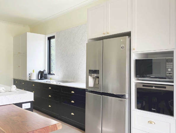 Modern kitchen with black and white cabinetry, stainless steel refrigerator, wall oven, microwave, and marble backsplash. Modern kitchen with black and white cabinetry, stainless steel refrigerator, wall oven, microwave, and marble backsplash.