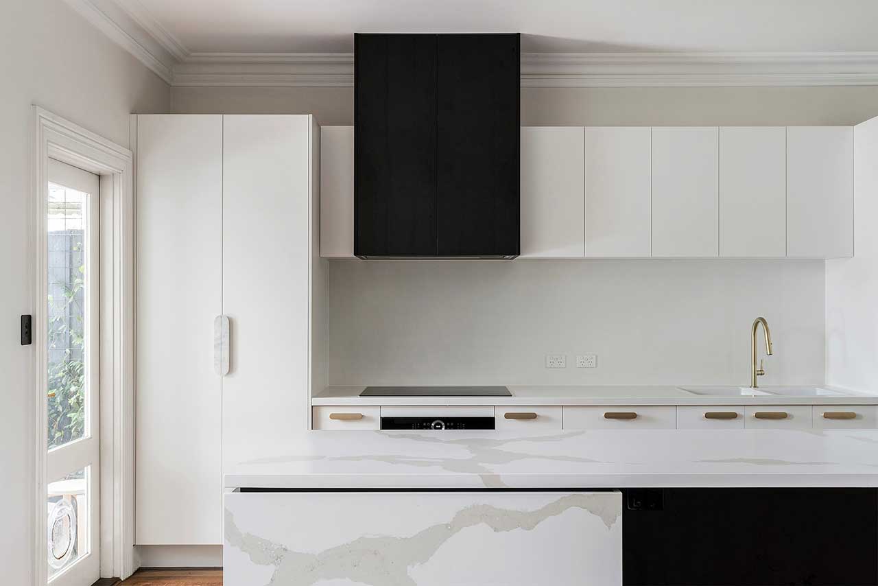 Modern kitchen with white cabinets, black range hood, and marble island. Gold faucet and natural light from door. Modern kitchen with white cabinets, black range hood, and marble island. Gold faucet and natural light from door.