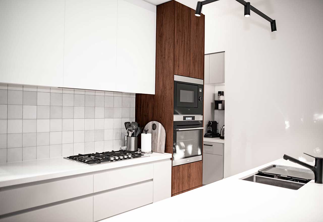 Modern kitchen with white cabinets, wood accents, built-in oven, stovetop, and sink. Minimalist and sleek design. Modern kitchen with white cabinets, wood accents, built-in oven, stovetop, and sink. Minimalist and sleek design.