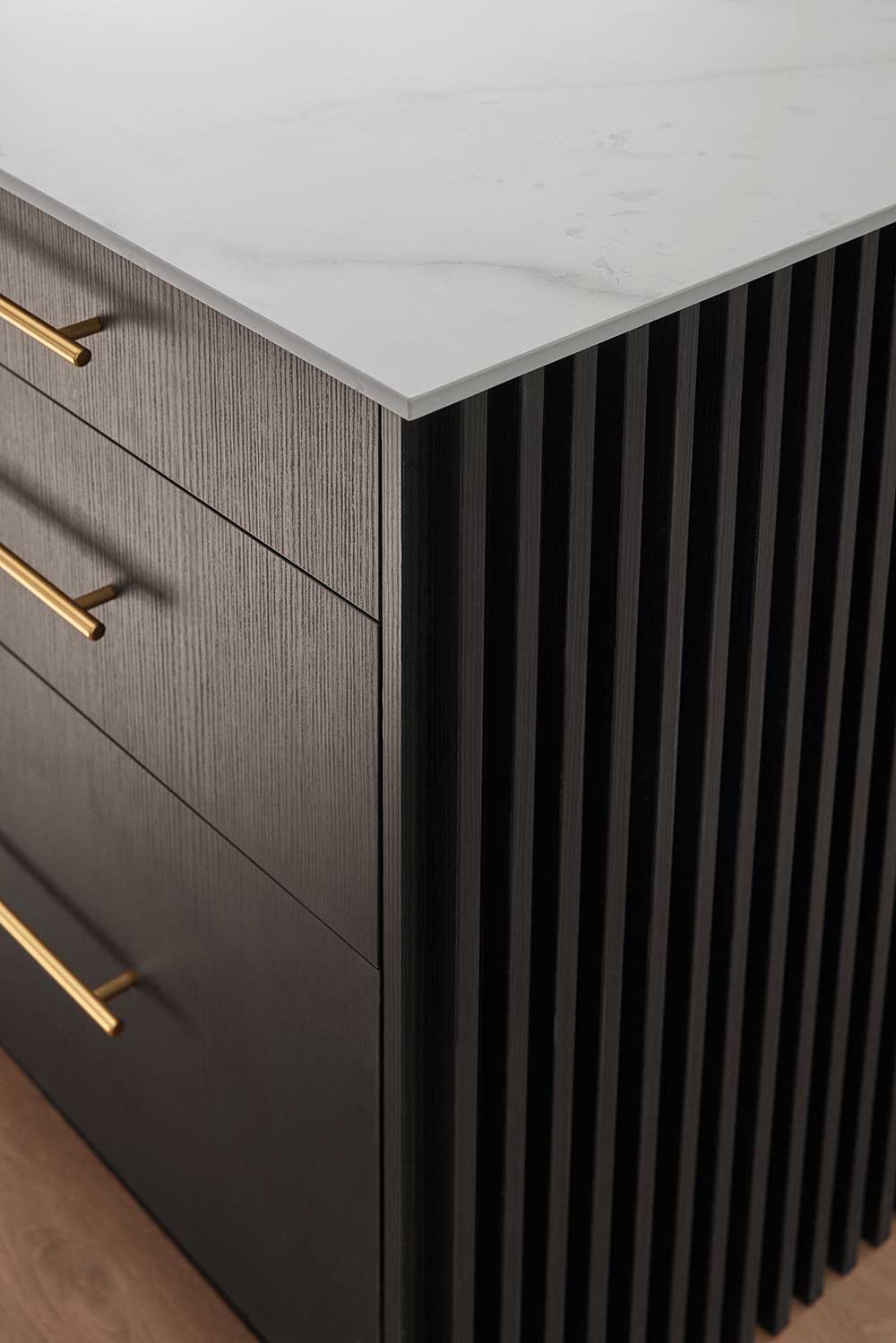 Black wooden cabinet with vertical grooves, gold handles, and a white marble countertop. Black wooden cabinet with vertical grooves, gold handles, and a white marble countertop.