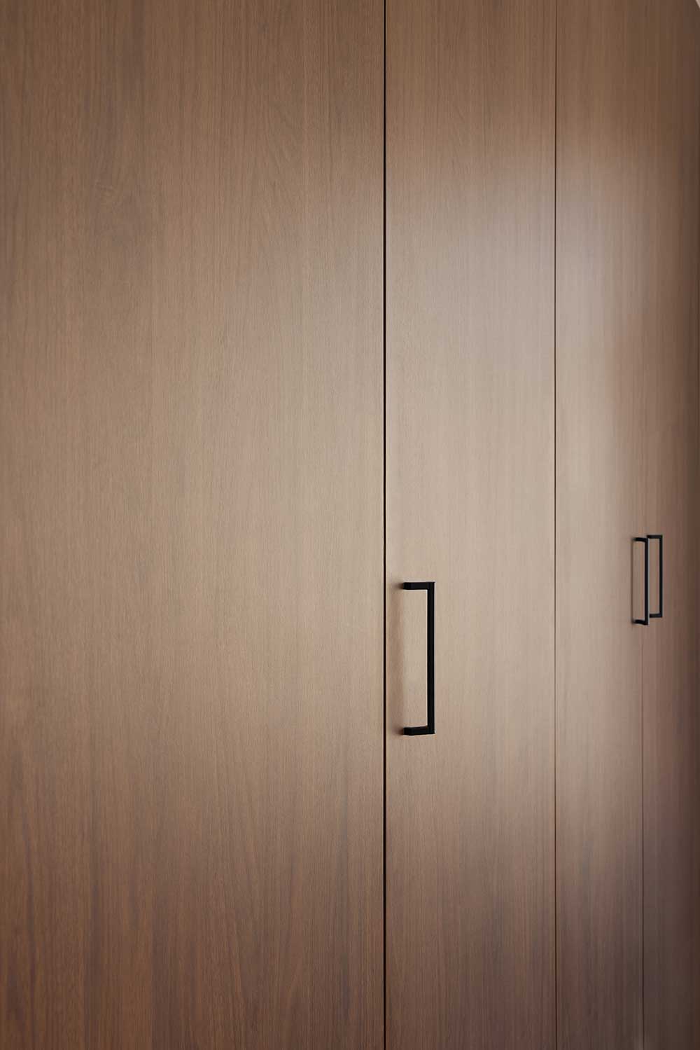 Wooden closet doors with minimalist black handles. Wooden closet doors with minimalist black handles.