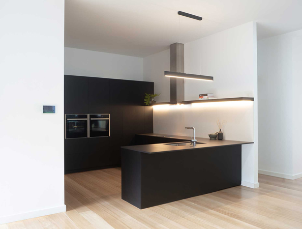 Minimalist kitchen with dark cabinets, island with sink, slim pendant lights, and light wooden flooring. Minimalist kitchen with dark cabinets, island with sink, slim pendant lights, and light wooden flooring.
