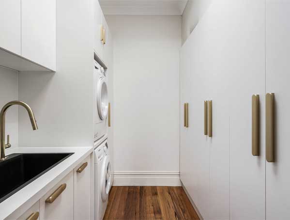 Modern laundry room with white cabinets, stacked washer and dryer, a black sink, and wooden floor. Modern laundry room with white cabinets, stacked washer and dryer, a black sink, and wooden floor.