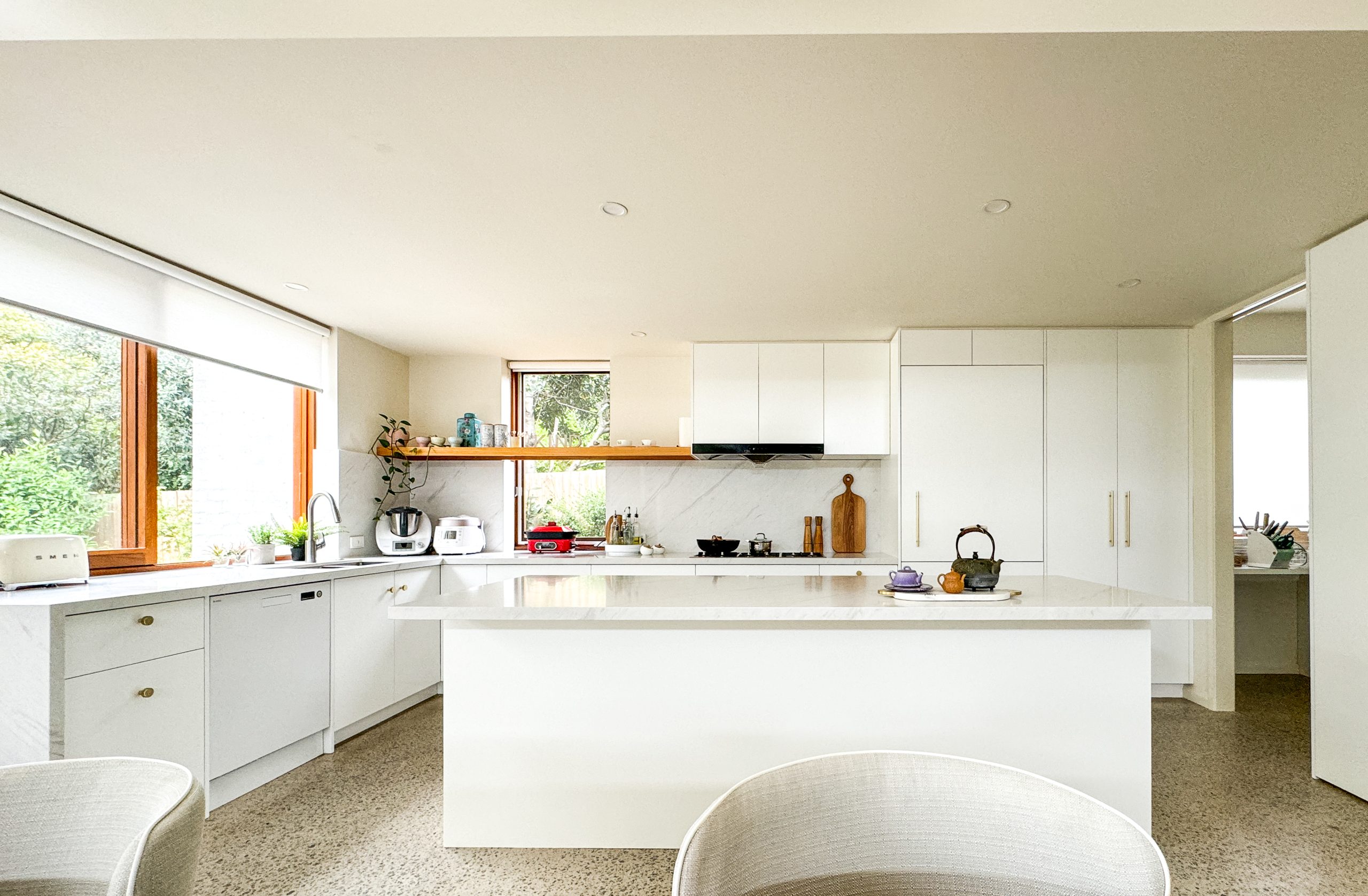 Bright modern kitchen with white cabinets, island, and large windows letting in natural light. Bright modern kitchen with white cabinets, island, and large windows letting in natural light.