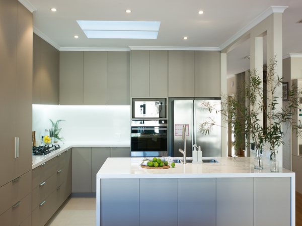 Modern kitchen with skylight, beige cabinets, stainless steel appliances, and white island with decorative plants.