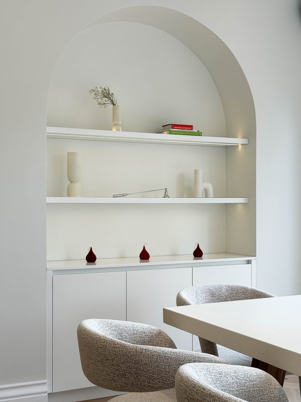 Arched display nook with bouclé armchairs